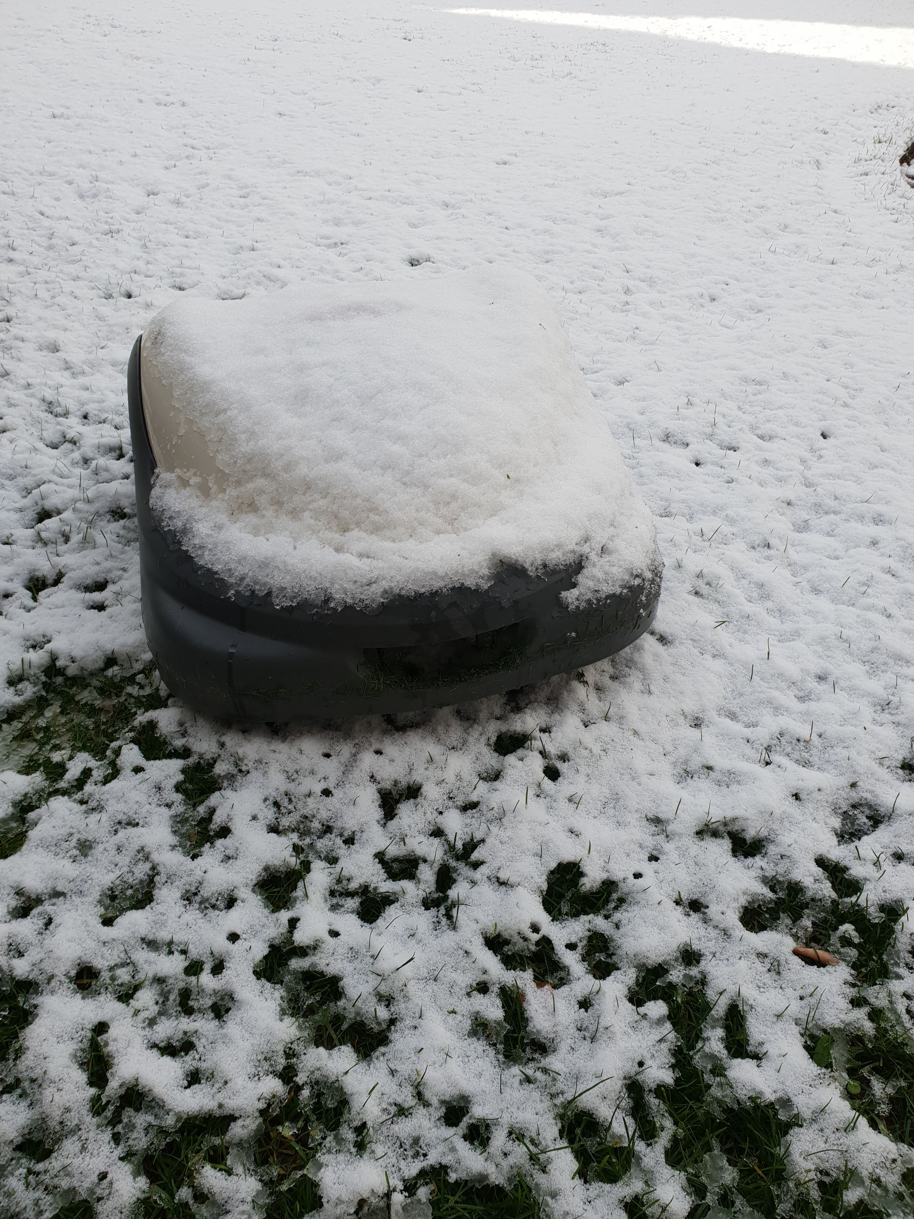 Rasenroboter im Garten von Schnee bedeckt während der Winterruhe